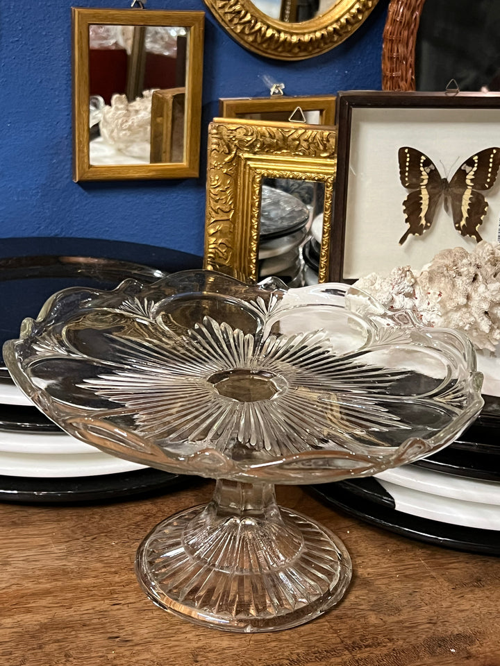 Alzata in vetro pressato vintage, perfetta per aggiungere un tocco di classe a qualsiasi ambiente. Con le sue linee morbide e il design ondulato del bordo, questa alzata è ideale per servire dolci, torte e frutta o come elemento decorativo su un tavolo da pranzo o un mobile.
Misure 26x15 cm