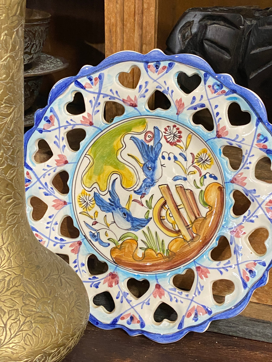 Piccolo piatto di forma tonda in ceramica portoghese dipinto a mano arricchito da intagli e una decorazione con protagonista due uccelli eseguita a mano.  Diametro 19,5 cm