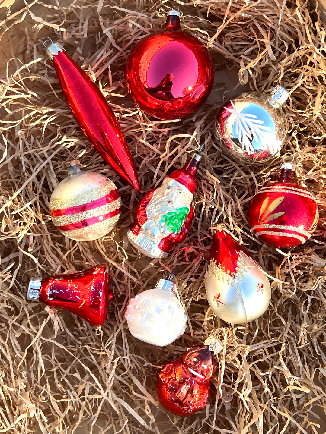 Set di dieci palline in vetro vintage dai toni dell'argento e del rosso. Pezzi unici, piani di storia ed incanto, pronti a brillare sul tuo albero.