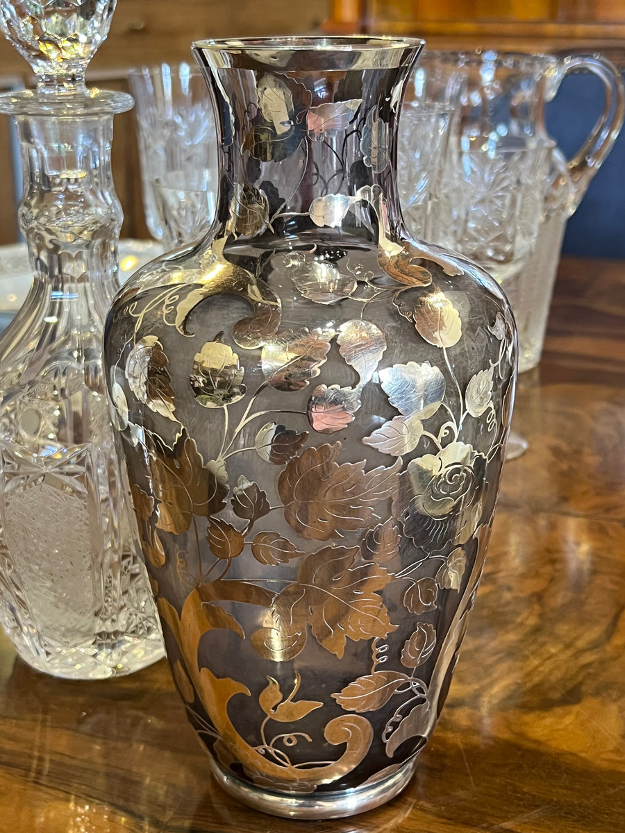 <p>Vaso in vetro color fume con motivo floreale e fogliaceo in argento realizzato in Italia nella metà del Novecento.</p> <p>Misure diametro 13 cm Altezza 26 cm</p>