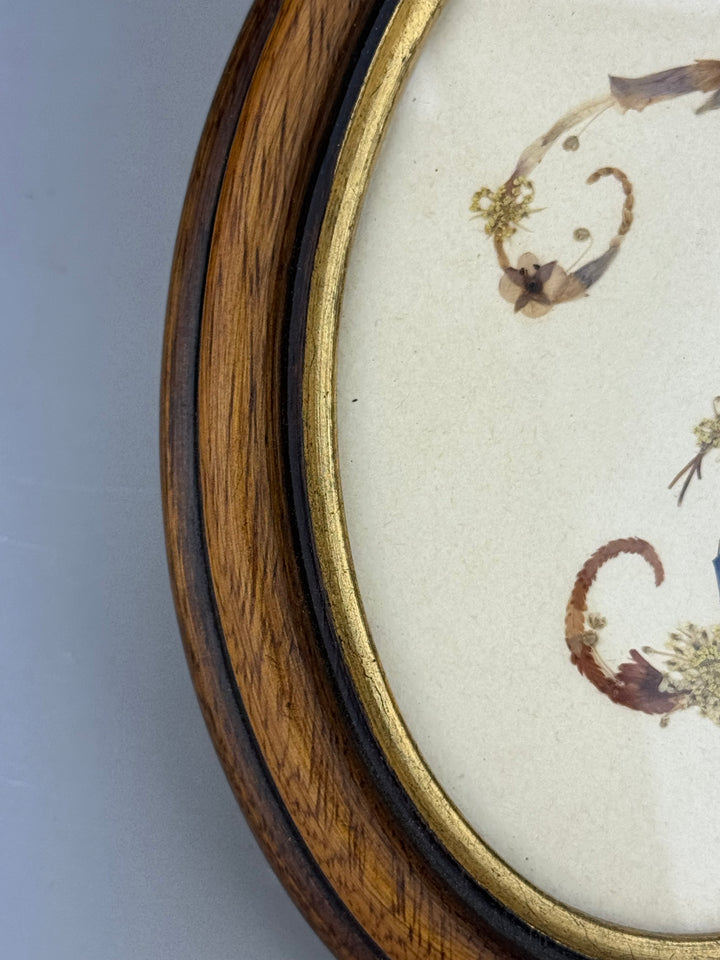 Quadretto ovale con iniziale “F” realizzata con fiori secchi pressati