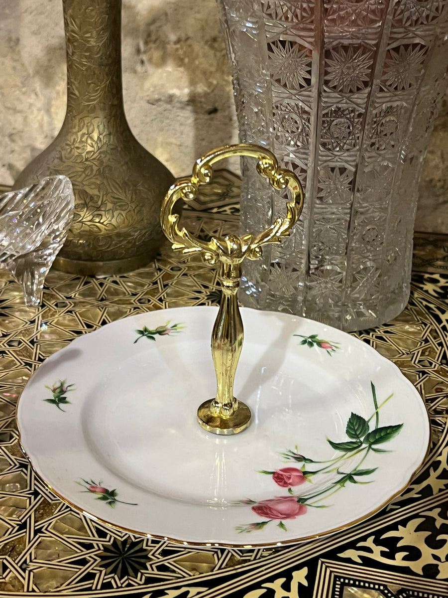 Delicata alzatine in porcellana con decorazione di rose, ideale per servire dolci, biscotti o piccole delizie abbellito dal manico dorato. Un accessorio perfetto per aggiungere un tocco chic alla vostra tavola.

Diametro 18 cm altezza 15 cm