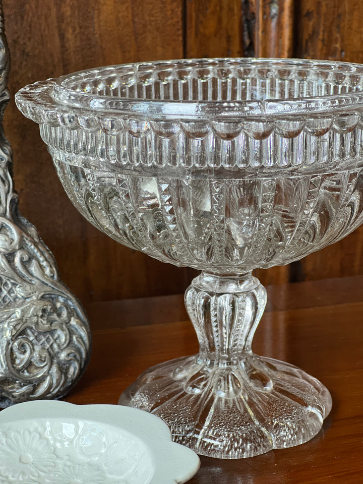 Deliziosa Alzatina in vetro con piedistallo, lavorazione dettagliata e bordo ondulato.&nbsp;

Perfetta per esporre dolci, frutta o come centrotavola decorativo, è ideale per aggiungere un tocco di eleganza a qualsiasi tavola o arredamento.&nbsp;

Dimensioni:&nbsp;16,5x15 cm