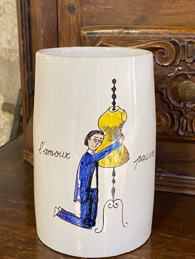 Boccale in ceramica della manifattura "Il cardo d'oro" attiva tra il 1947 e il 1958" a Firenze. Vi è raffigurata una rappresentazione del "Amore povero" scritto in francese. Facente parte di una serie sulle varie forme dell'amore in vendita nel nostro negozio.  Misure 14x15x9 cm