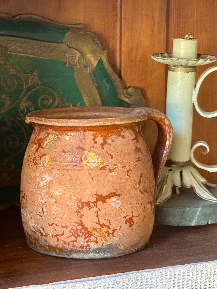 Brocca antica in terracotta smaltata con patina rustica e manico laterale.