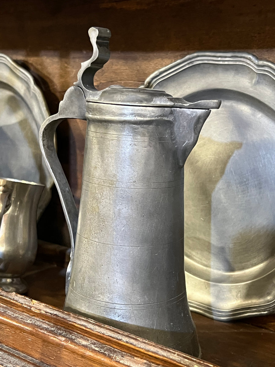 Brocca da birra in peltro massiccio con un design classico e robusto ispirato alle brocche utilizzate in passato.

&nbsp;La parte superiore è dotata di un coperchio che si apre verso l'alto grazie a una leva finemente lavorata permettendo cosi di versare il contenuto. Il corpo del boccale è decorato con sottili linee incise che corrono orizzontalmente, aggiungendo un tocco di eleganza alle sue linee semplici.

Misure 11x23 cm