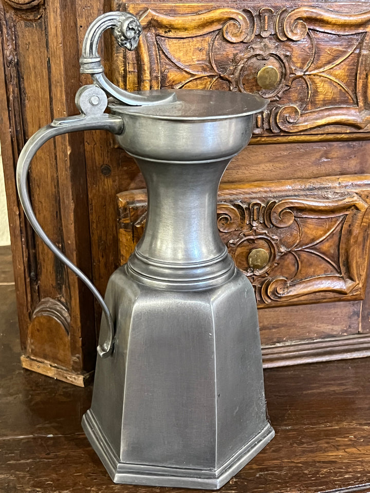 Brocca da birra in peltro caratterizzata da una forma robusta e geometrica con linee pulite e ben definite.&nbsp;L'impugnatura curva ed elegante presenta all'estremità superiore un decoro finemente lavorato.&nbsp;

L'equilibrio tra funzionalità e decorazione rende questa brocca un oggetto affascinante sia per l'uso quotidiano che per l'esposizione decorativa.

Misure 17x14x30h cm&nbsp;