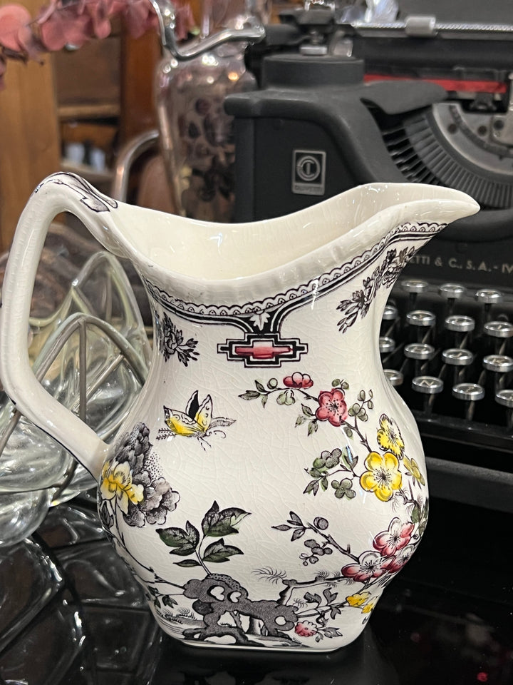 Elegante Brocca in porcellana Mason's decorata con il famoso motivo "Manchu", un design ricco di dettagli floreali e accenti orientali. Le delicate illustrazioni di fiori, farfalle e motivi geometrici in colori vivaci, come il giallo e il rosso, spiccano sul fondo bianco, creando un contrasto raffinato. Perfetta per chi ama lo stile classico inglese con un tocco esotico, questa brocca è ideale sia per l'uso quotidiano che come pezzo decorativo da esporre.&nbsp;

Misure 16x17x10,5 cm