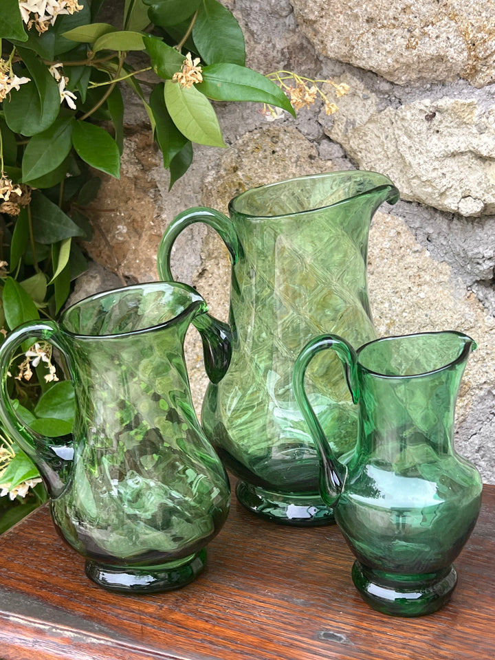 Deliziosa Brocca in vetro verde vintage.&nbsp;  Realizzata con cura artigianale, questa brocca presenta una bellissima texture ondulata che cattura e riflette la luce.  Perfetta per occasioni speciali o per un uso quotidiano, aggiunge un tocco di colore alla vostra tavola.