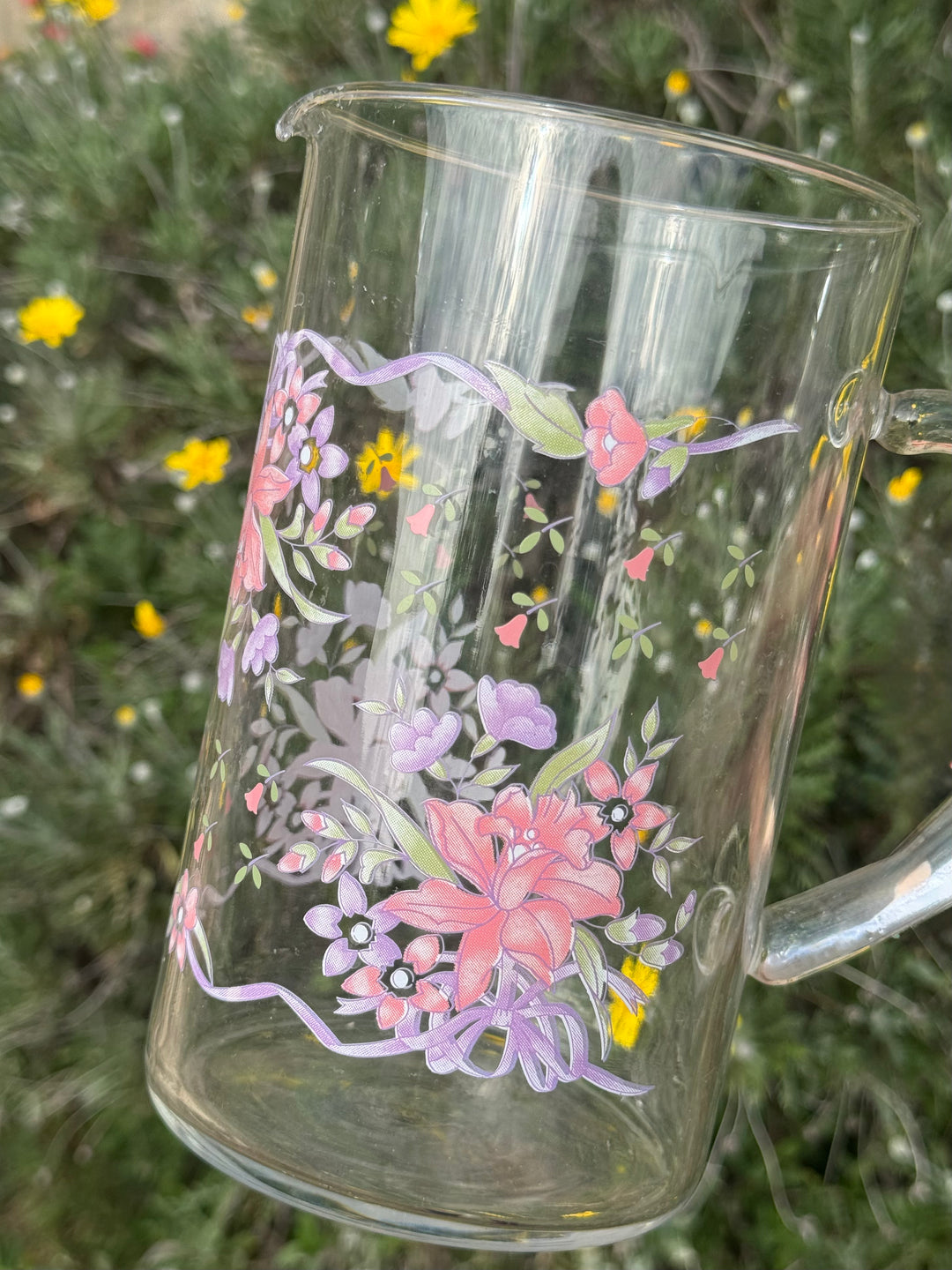 Brocca vintage Arcopal in vetro trasparente con manico e decorazione floreale rosa corallo, lilla e verde.