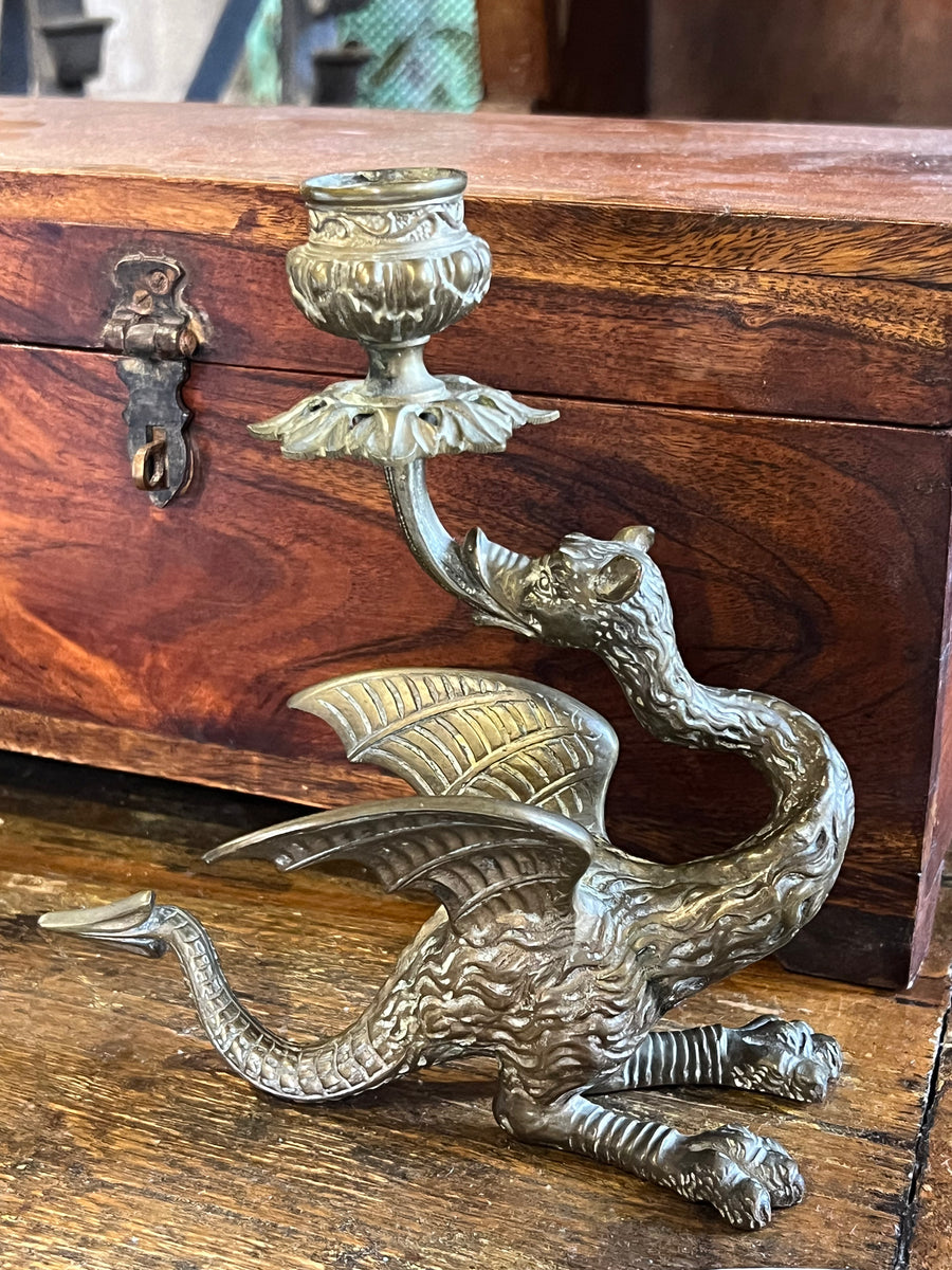 Suggestivo Candelabro in ottone, modellato con cura artigianale nella forma di un drago alato dalle linee sinuose e dettagliate. Il braccio porta candela si solleva dalla bocca della creatura, creando un effetto scenografico e fiabesco.

Misure 17x7x19 cm&nbsp;

Ideale per chi ama il fascino del mitologico o cerca un oggetto scenografico da collezione.