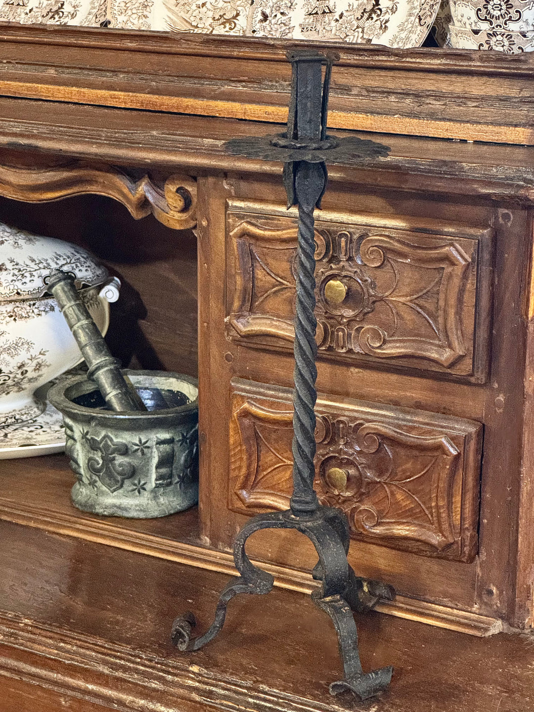 Candelabro in ferro battuto con stelo tortile e base a tre piedi in stile rustico.