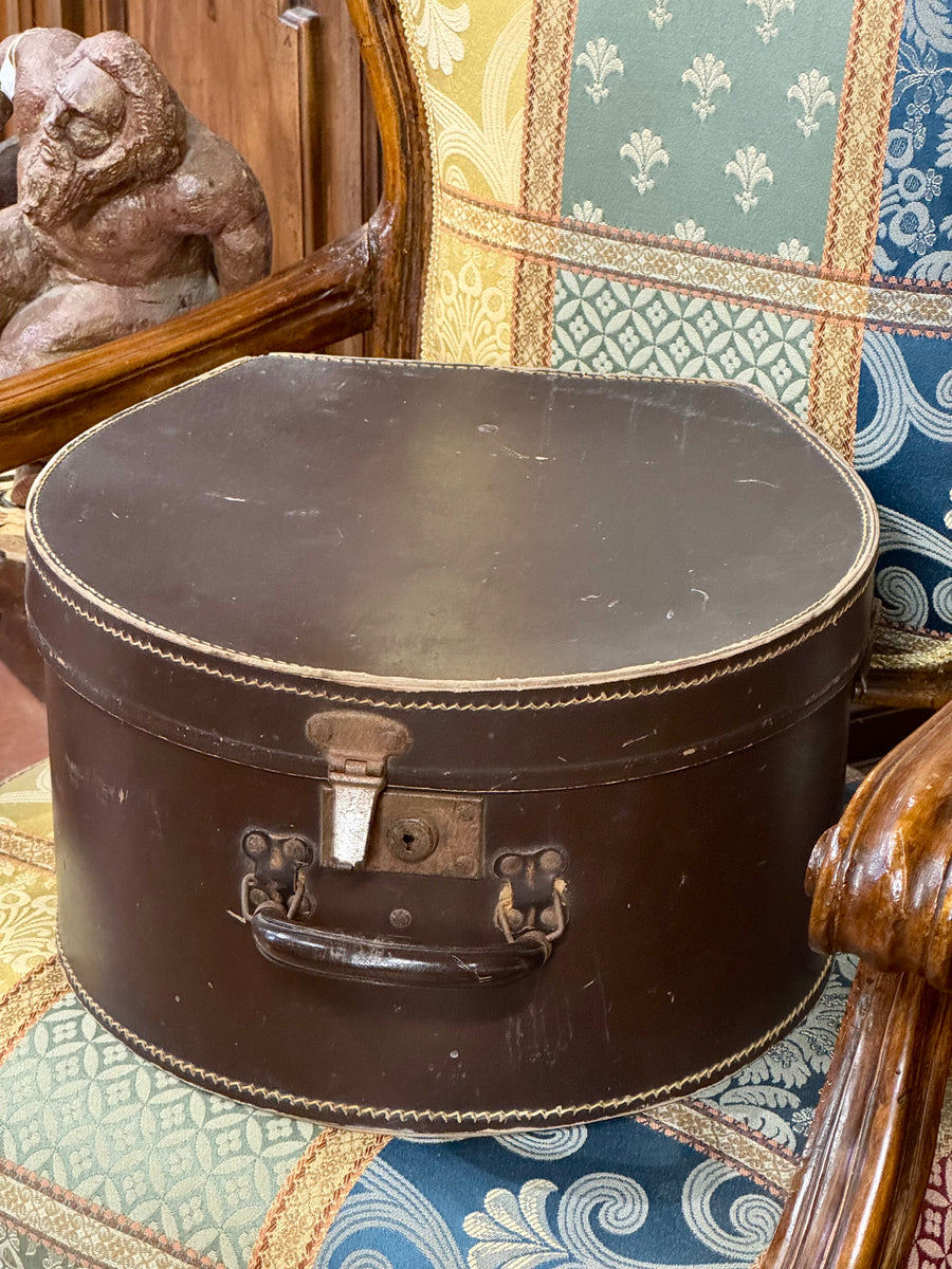 Cappelliera vintage in cuoio marrone con maniglia e interno originale rivestito in tessuto rigato.