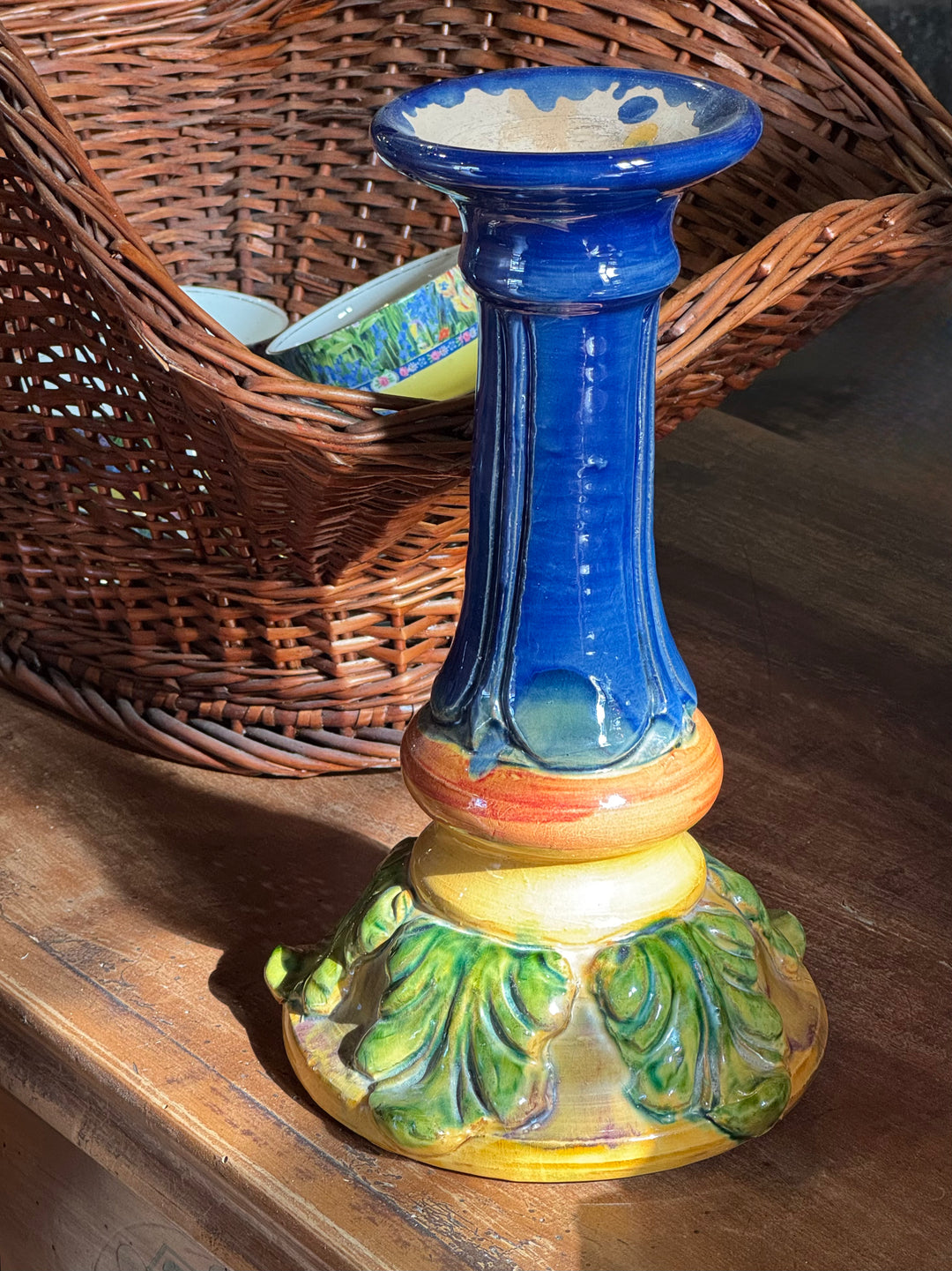 Grande portacandela in ceramica smaltata blu cobalto con fasce gialle e arancioni e base verde decorata con foglie in rilievo.