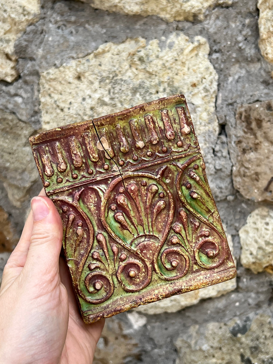 Mattonella decorativa in terracotta smaltata con motivi floreali e geometrici in rilievo, realizzata nei toni del verde e del marrone.

La superficie presenta una patina del tempo che ne accresce il fascino vintage.&nbsp;

Misure 10,5x12,5 cm