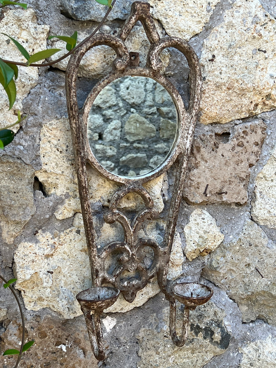 Portacandele a due luci in ferro battuto effetto anticato arricchito da un piccolo specchio circolare incastonato.

Grazie al suo fascino rustico dona a qualsiasi ambiente un tocco di charme antico.&nbsp;

Misure 22x12x55 cm&nbsp;