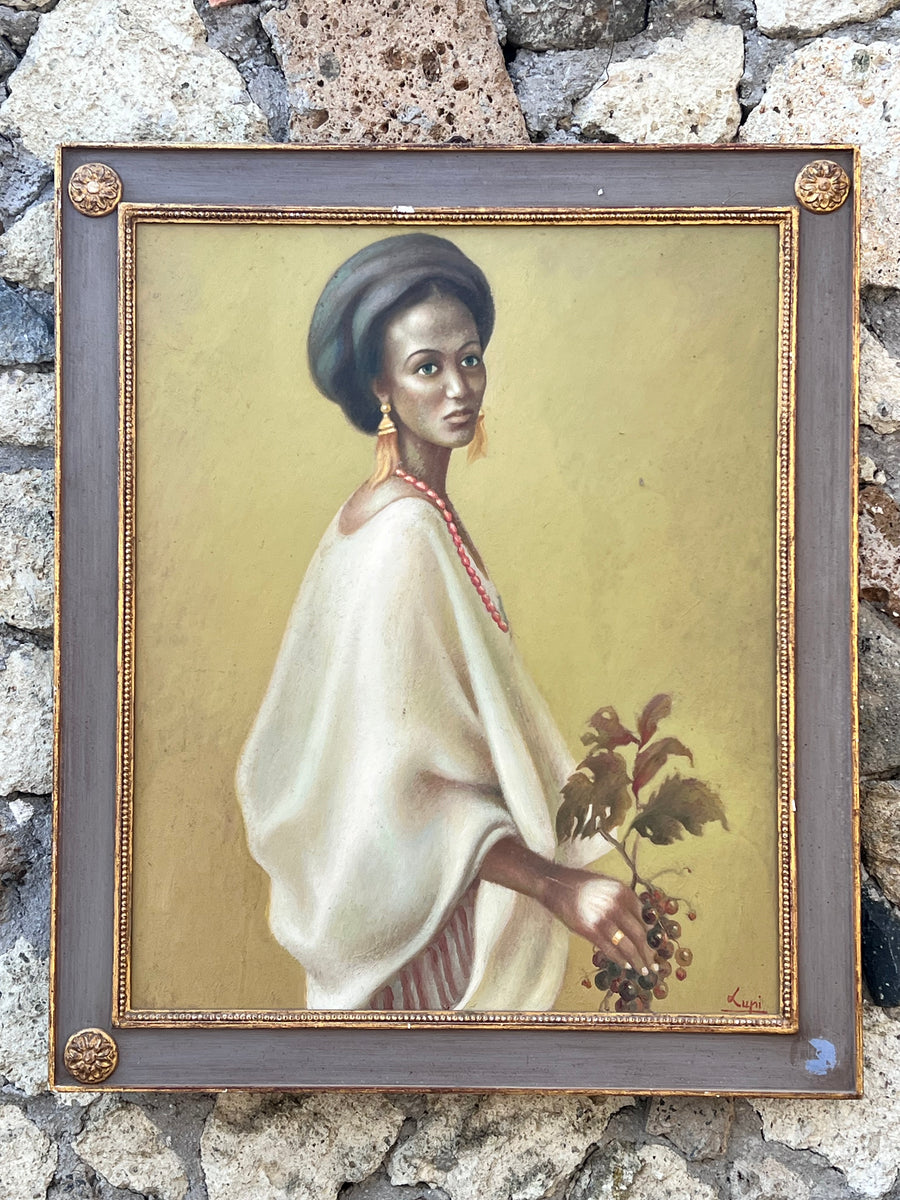 Quadro olio su tavola che ritrae una donna di origini etiope in posa con un grappolo l'uva in mano firmato Lupi.  E' adornato da una cornice in legno di colore grigio e con dettagli e decoro dorati.  Misure 85x100 cm