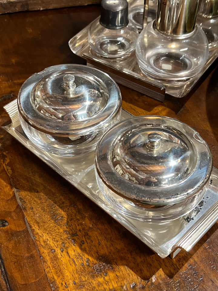 Set condimenti firmato Peruzzi &amp; Bozzi, composto da due contenitori in vetro trasparente con coperchi in silverplate e completo di vassoio. Un'accessorio da tavola perfetto per contenere salse, condimenti o spezie, aggiungendo un tocco di classe.

Misure Vassoio 22x10 cm Contenitore&nbsp;10x8 cm
