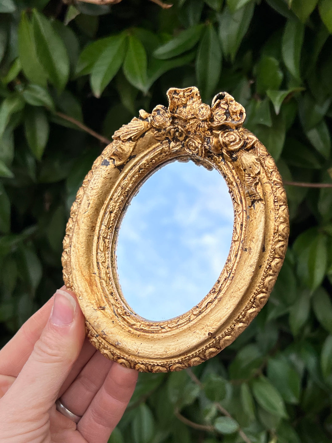 Specchietto di misure 13x10 cm, di ispirazione Luigi XVI con cornice intagliata e dorata a foglia oro. Nella parte superiore è presente un delicato fiocchetto e un dettaglio floreale. Con una maestria che trascende il tempo, i nostri specchietti sono capolavori realizzati a mano che catturano l'essenza dell'eleganza barocca. Ogni cornice, finemente scolpita e rifinita con foglia d'oro, è frutto di tecniche di antichizzazione che regalano un'anima vissuta e senza tempo ad ogni pezzo.