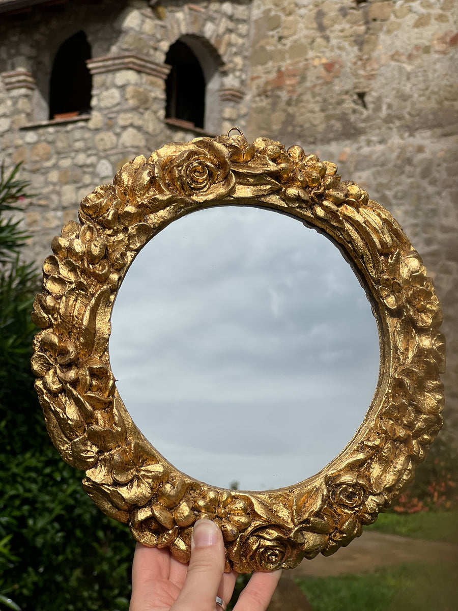 Specchietto di diametro 26 cm, di ispirazione barocca con cornice intagliata e dorata a foglia oro. Su tutta la cornice è presente un elegante motivo floreale.

Con una maestria che trascende il tempo, i nostri specchietti sono capolavori realizzati a mano che catturano l'essenza dell'eleganza barocca. Ogni cornice, finemente scolpita e rifinita con foglia d'oro, è frutto di tecniche di antichizzazione che regalano un'anima vissuta e senza tempo ad ogni pezzo.
