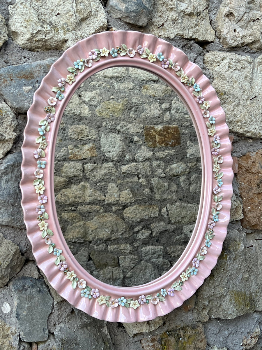Meraviglioso Specchio da parete ovale in ceramica smaltata italiana "La Farnesina Parma" caratterizzato da un bordo ondulato rosa con un delicato motivo floreale. Perfetto per dare un tocco di charme in una camera per bambini, un bagno o un ingresso.

Provvisto di ganci che permettono di appendere lo specchio sia in verticale che in orizzontale.

Misure 65x 50 cm