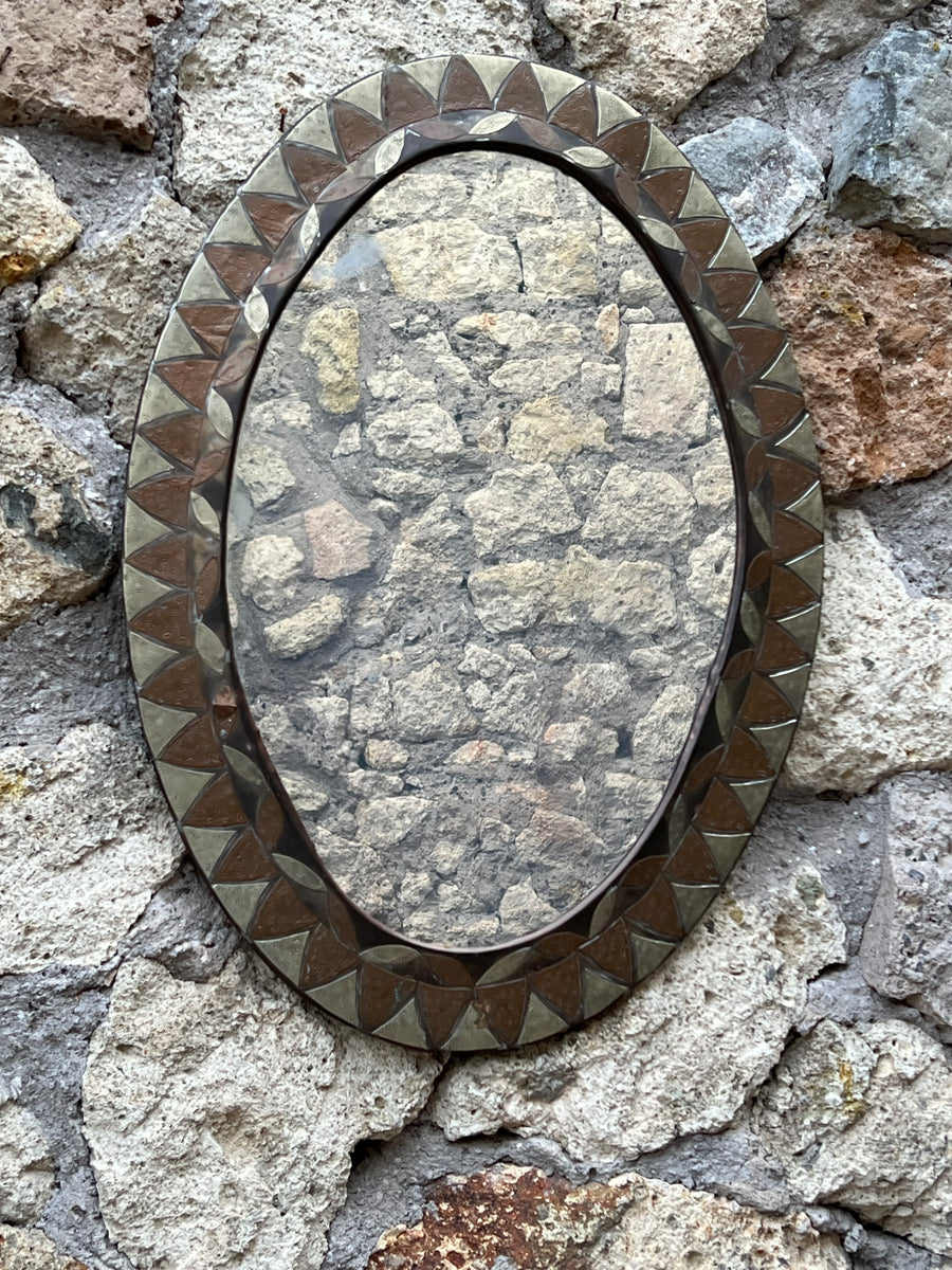 <p>Specchio ovale con cornice in rame e ottone con disegno geometrico.</p> <p>Misure 60x43 cm</p>