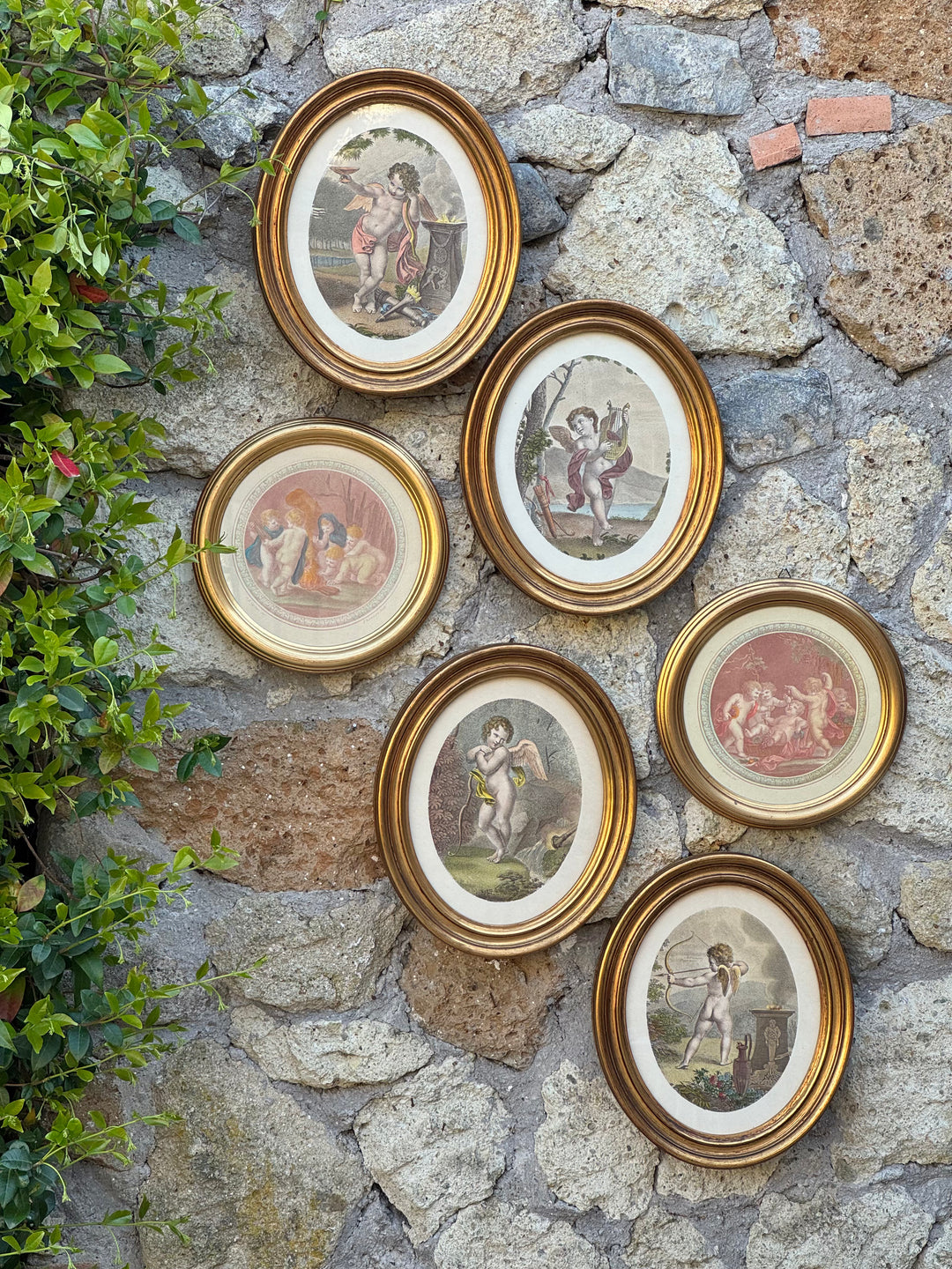 stampe decorative con putti e amorini in cornici ovali dorate disposte a parete