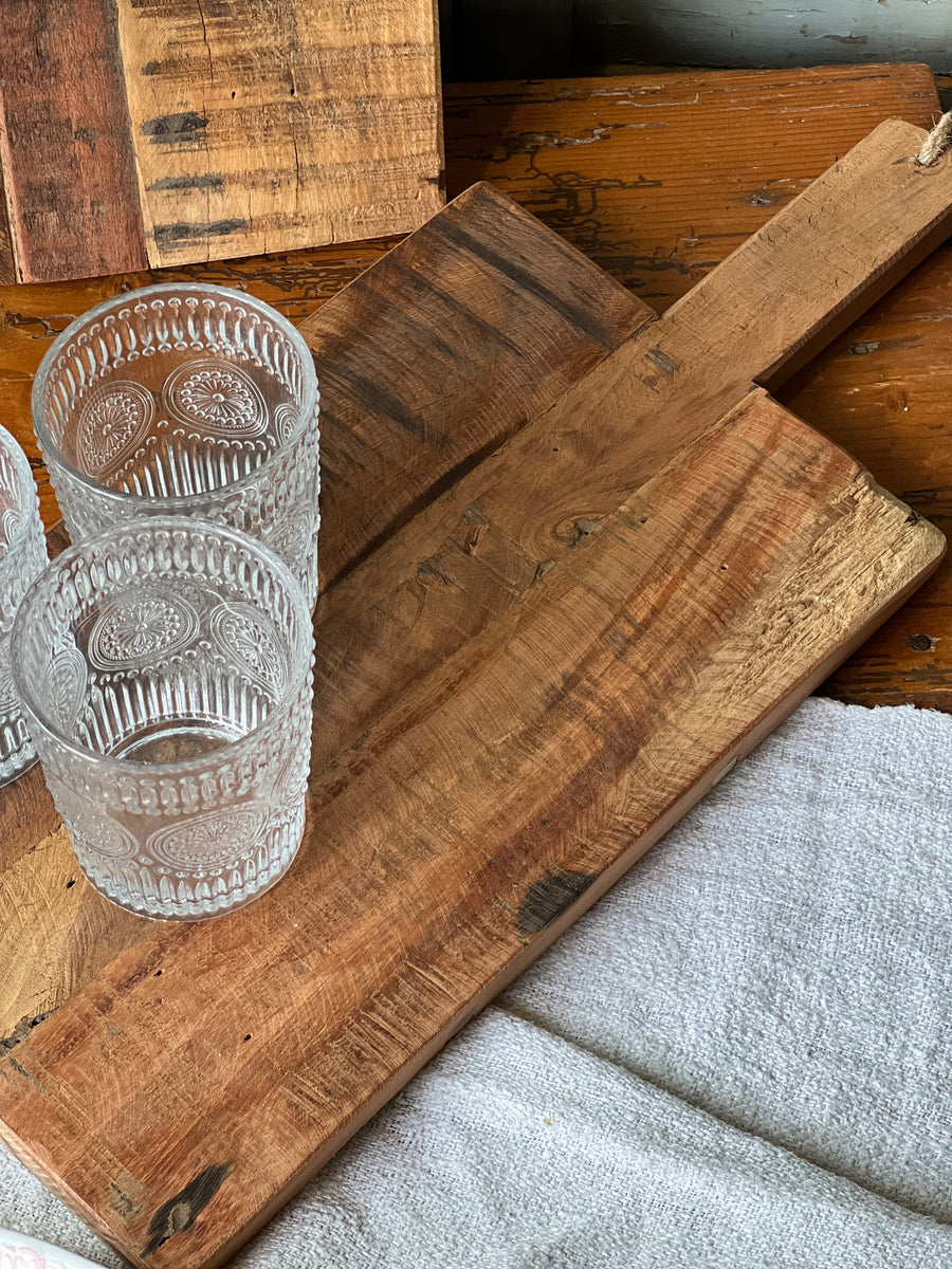 Tagliere realizzato in legno rustico e caratterizzato da un design robusto e una pratica maniglia con corda per appenderlo. Ideale sia per l’uso quotidiano in cucina che come elemento decorativo, questo tagliere è perfetto per servire qualsiasi pietanza, regalando un tocco rustico e fascino naturale all'ambiente.

Misure 46x20,5 cm