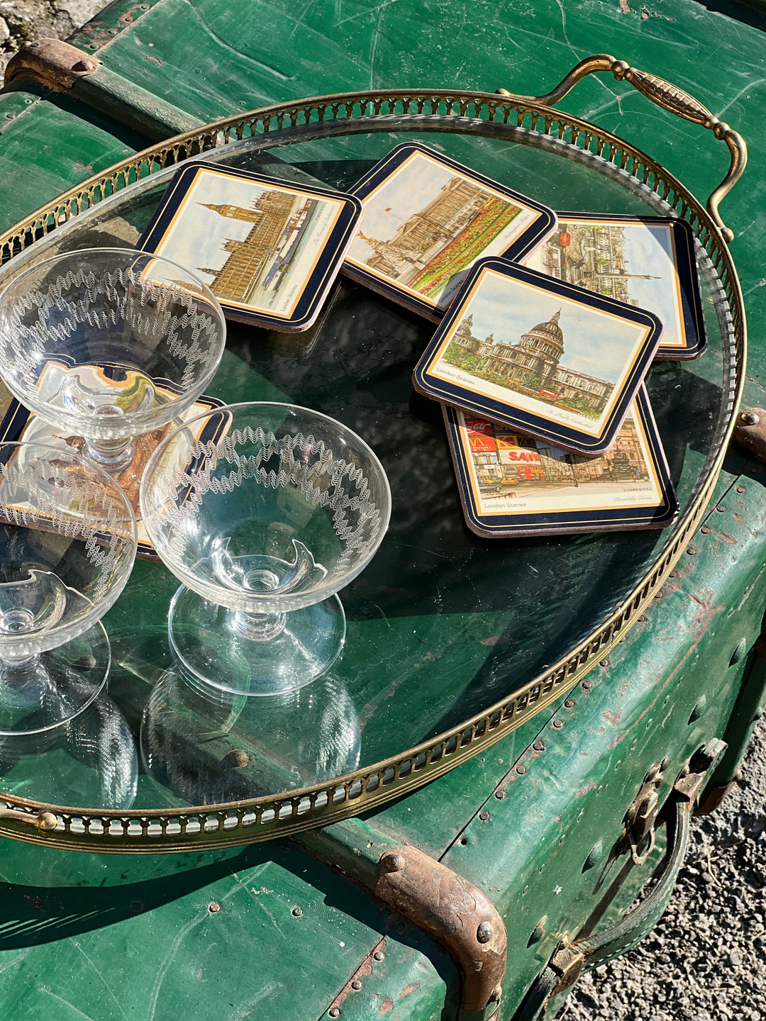 Vassoio ovale in vetro con ringhiera traforata in ottone, con bicchieri vintage e sottobicchieri su fondo verde