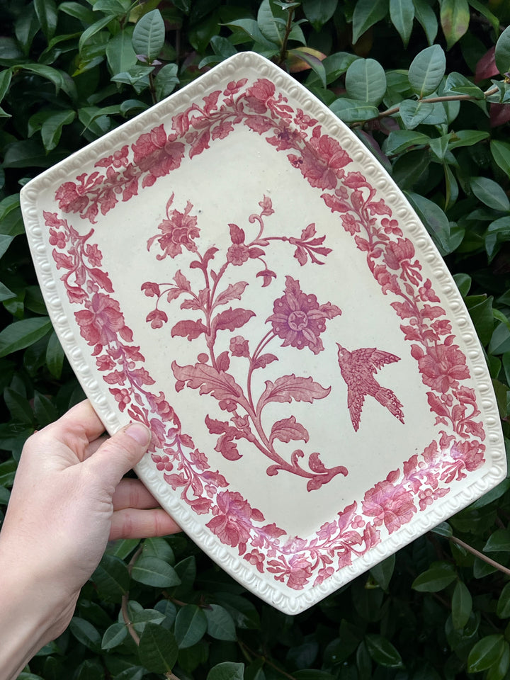 Elegante vassoio in ceramica firmato Copeland, decorato con un raffinato motivo floreale e arricchito da un bordo in filigrana. L'immagine centrale presenta un uccello in volo tra i fiori, che dona leggerezza e raffinatezza all'oggetto.Un oggetto ideale per decorare o servire con stile, perfetto per collezionisti e amanti del vintage.

Misure 29x21 cm