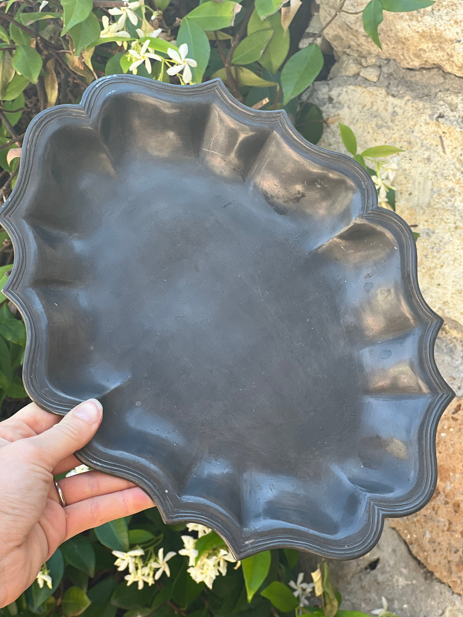 Vassoio vintage in peltro con bordo sagomato tenuto in mano, fondo floreale