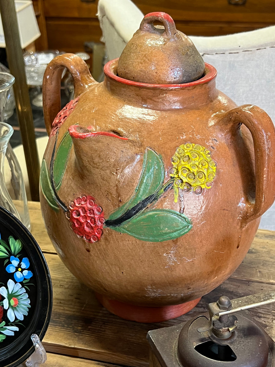 <p>Vecchia Giara in terracotta con decorazione floreale incisa e dipinta e bordo rosso.</p> <p>Completa di tappo e manici ai lati.</p>