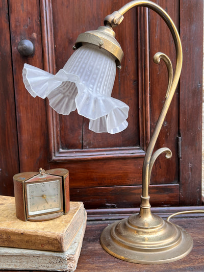 Abat-jour in stile Art Nouveau a forma di fiore. La base e il gambo della lampada è in ottone e la coppa, leggermente orientabile, in vetro satinato.