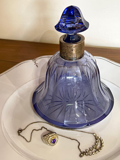 Bottiglia in cristallo viola mid-century. Base circolare, sul collo rivestimento in metallo placcato argento che ospita il tappo a punta.  