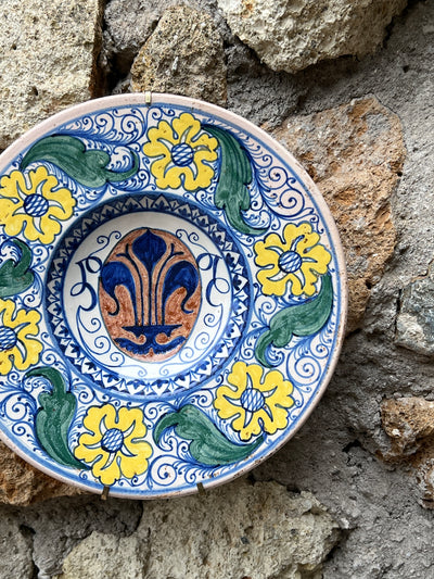Piatto in ceramica con decoro floreale dipinto eseguito a mano.