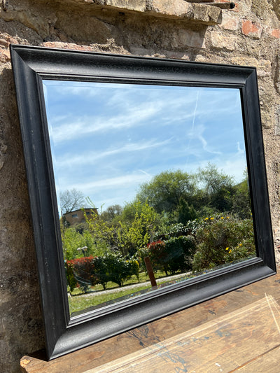 Specchio rettangolare con cornice in legno di colore nero.